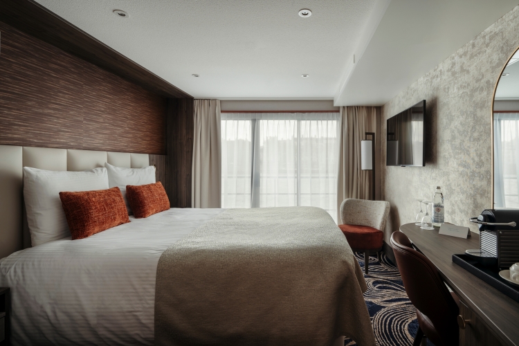 Hotelzimmer mit Doppelbett, Schreibtisch und Fernseher.