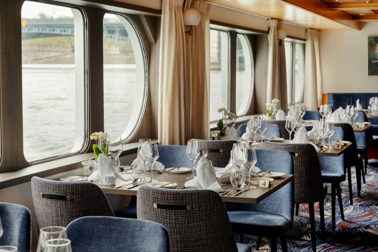 Ein Schiff-Restaurant mit gedeckten Tischen und Blick auf das Wasser.