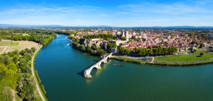 Luftaufnahme einer Flusslandschaft mit Stadt und Brücke bei klarem Himmel.