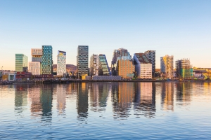 Stadtpanorama mit modernen Gebäuden spiegelt sich im Wasser bei Sonnenuntergang.