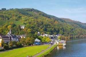 Uferpromenade in Traben-Trarbach mit Fluss und bewaldeten Hügeln im Hintergrund.