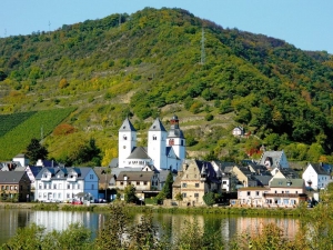 Stadtansicht von Zell an der Mosel mit Kirche und umliegenden Hügeln.