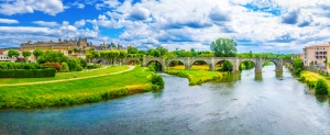 Steinbrücke über einen Fluss mit historischer Stadt im Hintergrund.