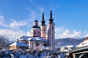 Barockkirche im Schnee mit blauem Himmel im Hintergrund.