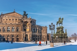 Historisches Gebäude und Reiterstatue im Schnee bei klarem Himmel.
