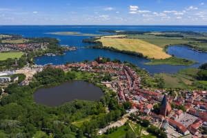 Luftaufnahme einer Stadtlandschaft mit Seen und Feldern im Hintergrund.