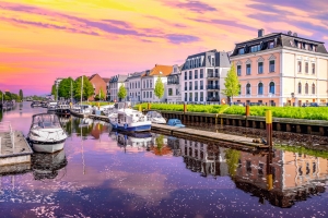 Fluss mit Booten und bunten Gebäuden bei Sonnenuntergang