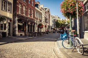 Maastrichter Straßen mit Kopfsteinpflaster, Fahrrad und Blumen im Sommer.
