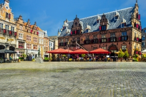 Historischer Platz mit alten Gebäuden und Straßencafés bei sonnigem Wetter.