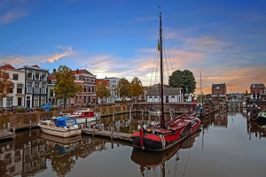 Hafen mit traditionellen Booten und historischen Gebäuden im Hintergrund bei Sonnenuntergang.