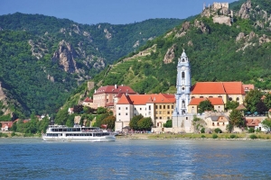 Vergnügungsschiff auf Fluss vor Stadt mit Kloster und Hügel im Hintergrund