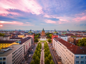 Blick auf eine Stadt mit Turm und umgebenden Gebäuden bei Sonnenuntergang.