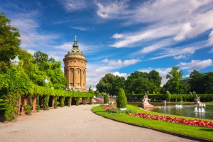 Wasserturm mit umliegender Parkanlage und Brunnen unter blauem Himmel