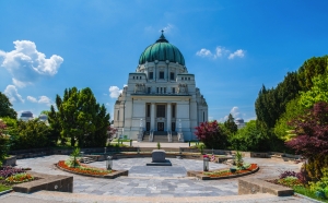 Mausoleum mit Kuppel und gepflegter Gartenanlage bei sonnigem Wetter.