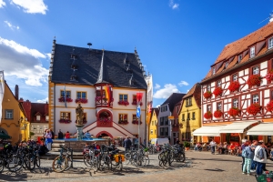 Historischer Marktplatz mit Fachwerkhäusern und dekorativen Fassaden bei Sonnenschein.