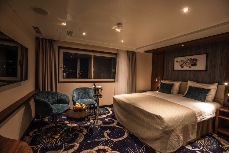 Modern eingerichtetes Hotelzimmer mit Doppelbett und Sitzbereich.
