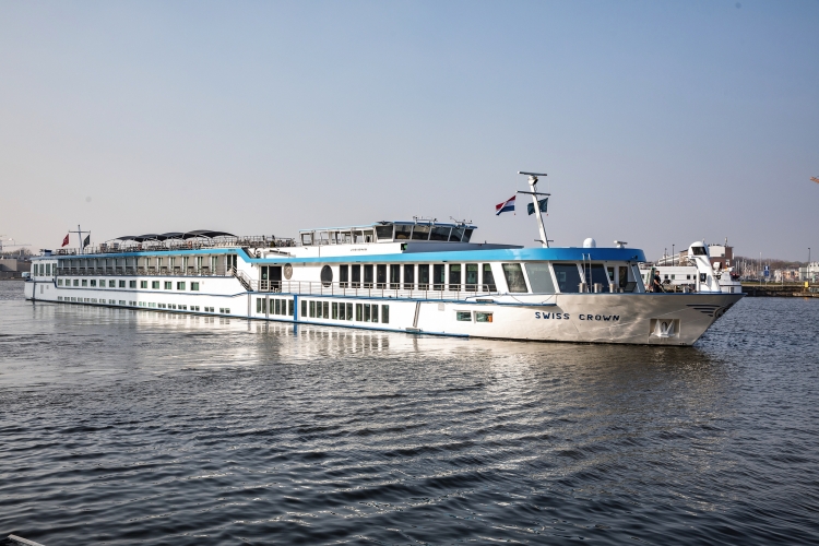 Kreuzfahrtschiff Swiss Crown auf einem Fluss bei klarem Himmel.