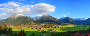 Idyllische Herbstlandschaft von Oberstdorf im Allgäu mit den Alpen im Hintergrund und einer malerischen Dorfansicht.