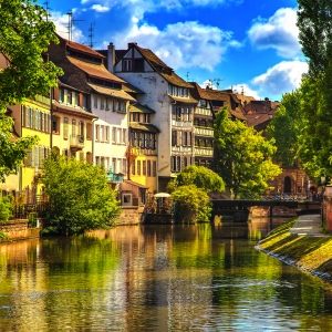 Historische Gebäude entlang eines Kanals in Straßburg, Elsass, bei klarem Himmel.