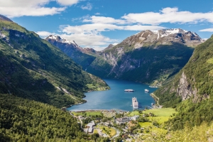 Blick auf den Geirangerfjord mit Bergen und einem Kreuzfahrtschiff im Wasser.