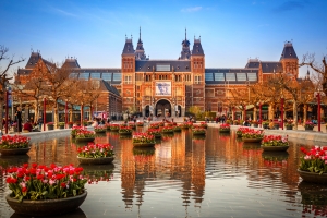 Rijksmuseum in Amsterdam im Frühling mit blühenden Tulpen und klarem Himmel im Hintergrund.
