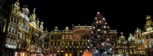 Illuminierter Platz mit historischem Gebäude und großem Weihnachtsbaum bei Nacht