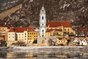 Stadtansicht mit Kirche an einem winterlichen Flussufer.