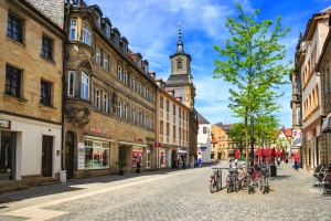 Straßenansicht mit historischen Gebäuden und Fahrrädern, klarer Himmel im Hintergrund.