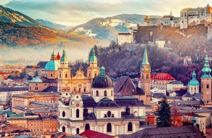 Stadtansicht mit historischen Gebäuden und Burg auf Hügel in Salzburg bei Sonnenuntergang