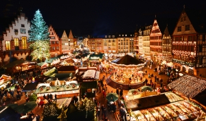 Weihnachtsmarkt mit geschmücktem Baum und Buden bei Nacht.