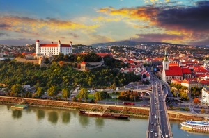 Stadtansicht von Bratislava mit Burg und Fluss bei Sonnenuntergang.