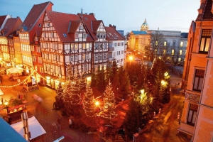 Weihnachtsmarkt mit festlich beleuchteten Buden und Tannenbäumen in Fachwerkumgebung.