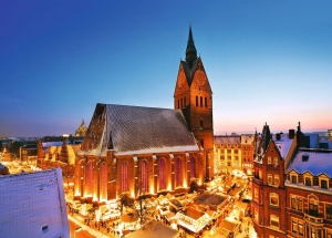 Kirche und beleuchteter Weihnachtsmarkt im Winter bei Dämmerung.