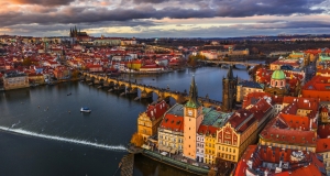 Blick auf die Karlsbrücke und die Stadt Prag bei bewölktem Himmel.