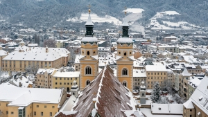 Stadtansicht im Winter mit schneebedeckten Gebäuden und zwei Kirchtürmen.