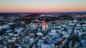 Verschneite Stadt mit Kirche bei Sonnenuntergang aus der Vogelperspektive.