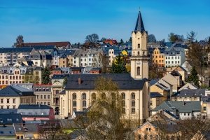 Panorama einer Stadt mit Kirche und umliegenden Häusern im Sonnenschein.