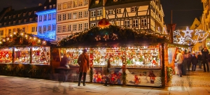 Weihnachtsmarkt mit beleuchteten Ständen und Fachwerkhäusern bei Nacht.