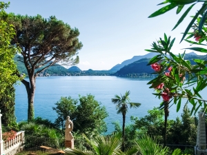 Blick auf einen See mit Palmen, Bergen und Statue im Garten.