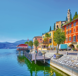 Bunter Stadthafen mit Gebäuden am Wasser und Bergen im Hintergrund.