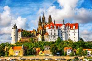 Schloss mit roten Dächern und Türmen unter blauem Himmel mit Wolken