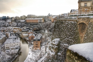 Winterliche Stadtansicht mit Fluss und schneebedeckten Gebäuden und Bäumen.