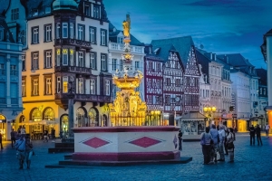 Historischer Marktplatz mit beleuchtetem Brunnen und alten Fachwerkhäusern bei Dämmerung.