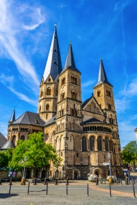 Gotische Kathedrale mit drei Türmen vor blauem Himmel.