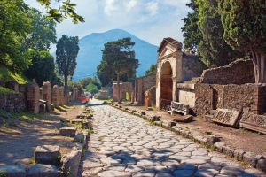 Antike gepflasterte Straße in Pompeji mit Vesuv im Hintergrund.