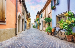 Bunte Häuser und Fahrrad in enger Gasse in Rimini, Italien bei Sonnenaufgang.