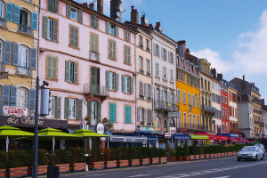 Bunte Gebäude und Cafés an einer Straße in einer Stadt.