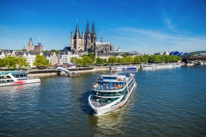 Kreuzfahrtschiff auf dem Rhein vor dem Kölner Dom bei sonnigem Wetter.