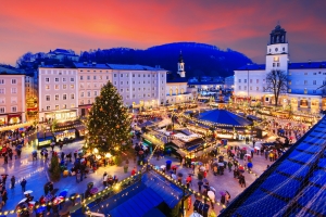 Weihnachtsmarkt in einer Stadt bei Sonnenuntergang mit beleuchtetem Tannenbaum