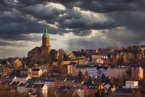 Panorama einer Stadt mit Kirche unter dramatischem Himmel.